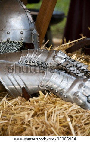a silver metal helmet and gloves lying in straw at a knight festival