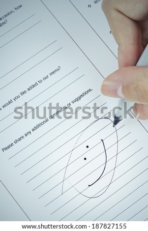 Hand drawing smiley face with black marker on service evaluation form, business feedback concept