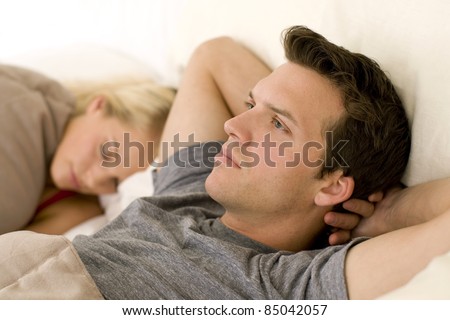Couple in bed, man looking worried