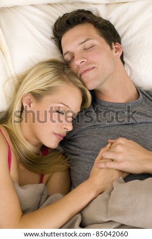 Attractive young couple asleep in bed