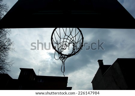 A close up of a basketball hoop silhouette shot from below at playground