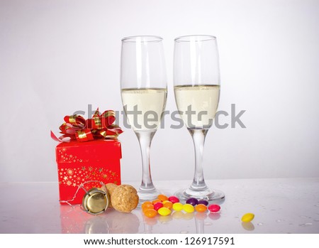 gift in a red box next to lie candy and glasses with wine