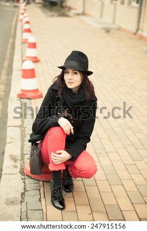 girl in a black hat sitting on the curb the outdoor