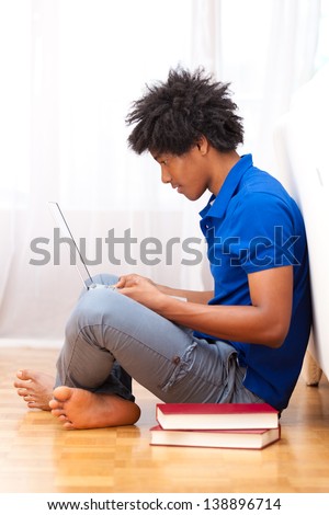 Young african american student seated on the floor using a laptop - African people