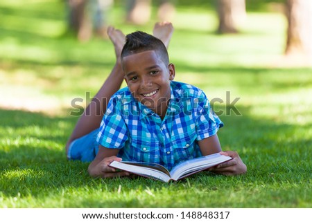 Outdoor portrait of student black boy reading a book - African people