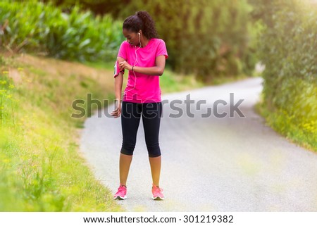 African american woman runner attaching music armband - Fitness, people and healthy lifestyle