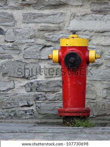 closeup of a red and yellow fire hydrant with a rock wall background