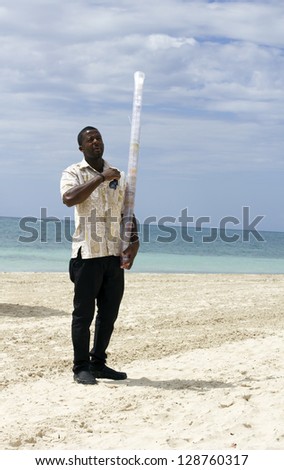 jamaican waiter holding a pile of empty glasses on the beach