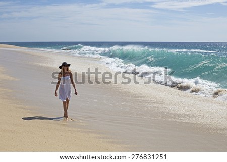 woman in bikini walking alone on the beach in a summer sunny day