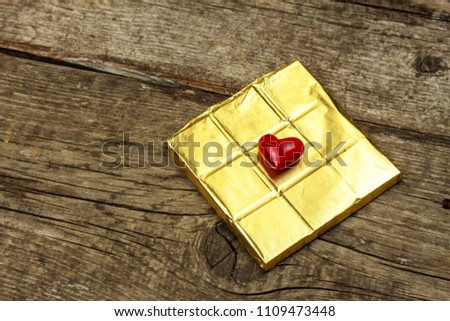 Bitter chocolate in a gold foil on a wooden board. Chocolate delicacy Foto stock © 