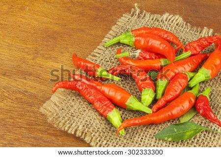 Freshly picked chili peppers on a wooden table. Preparation for the domestic processing of a crop. Decoration of chilli peppers. Place for text menu. Healthy fresh food.