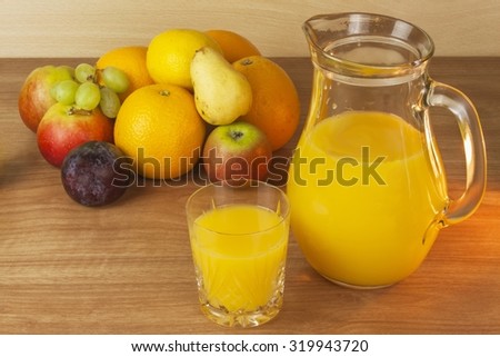 Production of summer fruit juices. Domestic fresh orange juice in a glass jar on a wooden table. Hand-prepared homemade orange juice. Healthy drink for athletes. Place for your text. Sales of juices.
