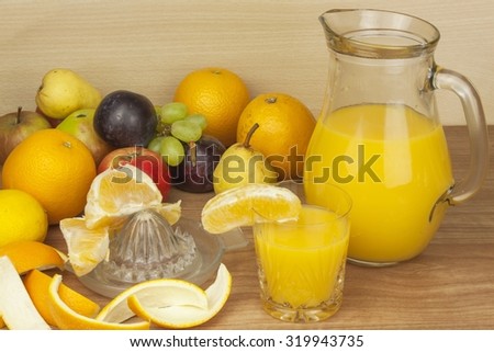 Production of summer fruit juices. Domestic fresh orange juice in a glass jar on a wooden table. Hand-prepared homemade orange juice. Healthy drink for athletes. Place for your text. Sales of juices.