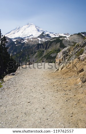 A hiking trail in Washington\'s North Cascades disappears into the distance with Mt. Baker in the background.