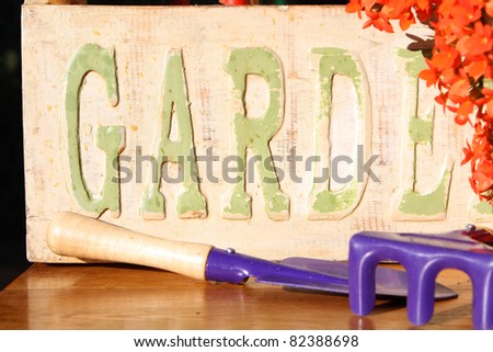 Ornate garden sign with orange flowers and purple garden tools