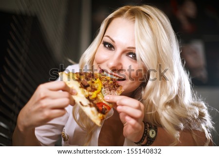 Young woman in a white shirt eats pizza