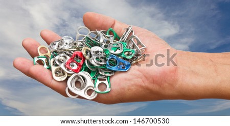 Group ring pull can opener on hand of man, Sky and clouds in the background.
