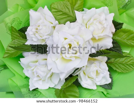 White artificial roses. Artificial flowers made ??from white plastic with green leaves.