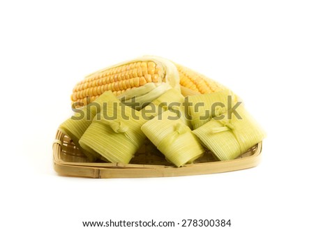 Corn pudding wrapped on green corn leaves isolated on white.