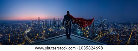 Businessman in suit and cape hero stand at rooftop looking great cityscape view and thinking business plan of the future . Night scene .