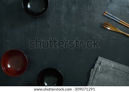 Black color wooden table top view. On the table are the Japanese wooden spoon, chopsticks, bowl and table linen.