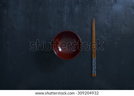 Black color wooden table top view. On the table are the Japanese wooden  chopsticks, bowl.