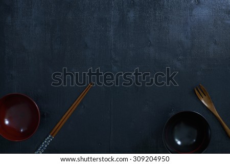 Black color wooden table top view. On the table are the Japanese wooden spoon, chopsticks, bowl.