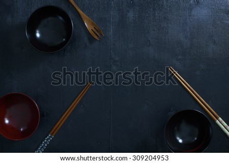Black color wooden table top view. On the table are the Japanese wooden spoon, chopsticks, bowl .