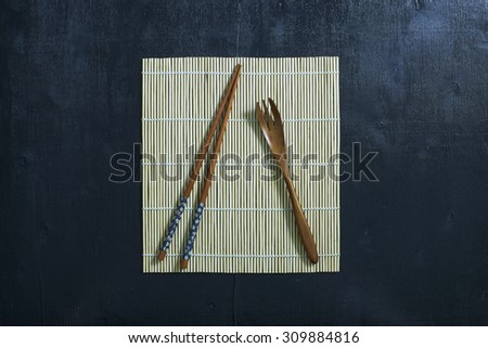Black color wooden table top view. On the table are the Japanese wooden spoon, chopsticks.