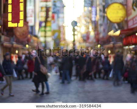 Crowds walk below the signs of Dotonbori. With a history reaching back to 1612, the district is now one of Osaka\'s primary tourist destinations. Abstract blur background .