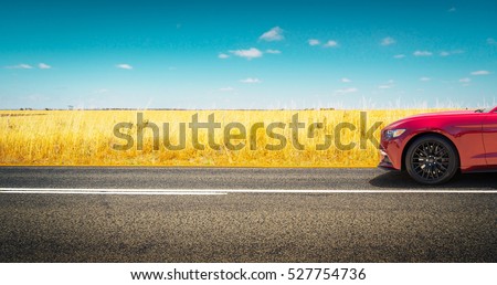 Sport car parked on road side with field of golden wheat background .