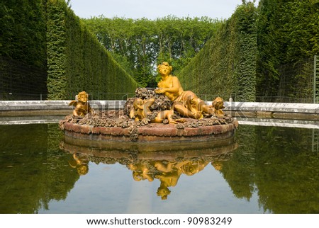Golden statue and inverted image of flora fountain in Versailles Palace garden, city Paris, France.