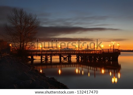 A fishing pier on the bank of the Fraser River near Steveston at first light. Mount Baker, in the Cascade Mountain Range, in the background. Richmond, British Columbia, Canada.