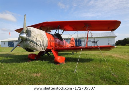 Vintage Red Biplane. A vintage red biplane secured to the ground at a small airfield.