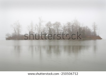 Fog Island. Calm water surrounds an island during a foggy day in the Pacific Northwest.