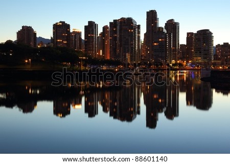 Vancouver condominiums and office towers at morning twilight behind Granville Island reflecting in the still water of False Creek. British Columbia, Canada.