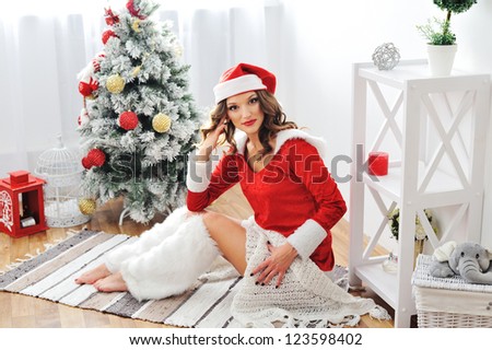 Beautiful happy woman in Santa Claus clothes Beautiful happy woman near Christmas tree