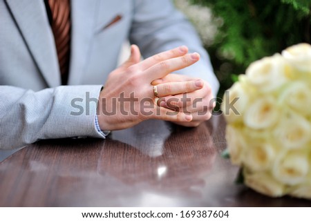 Groom is sitting at the table and twists the ring on her finger