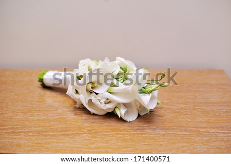 Wedding bouquet of bride lying on table. White flowers calla