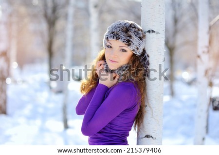 Outdoor winter portrait. Beautiful smiling girl posing in winter snowy forest
