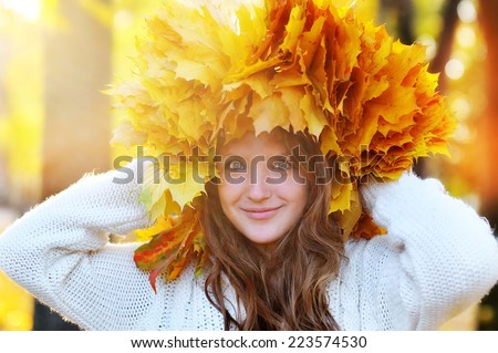 Beautiful red-haired young girl with a wreath of yellow and red leaves on the head.
