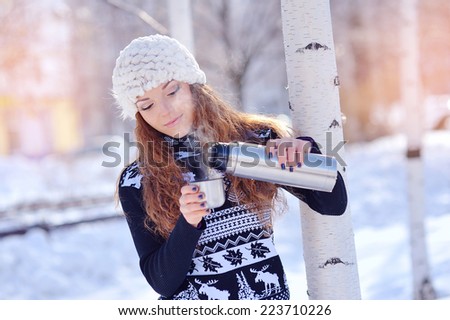 Girl drinking hot tea in the winter forest.