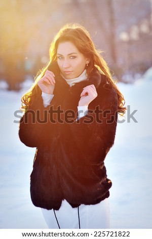 beautiful girl in winter fur coat. Backlit sunset sunshine.