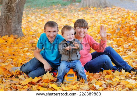 happy family, mother, father and son sitting on the autumn leaves yellow.