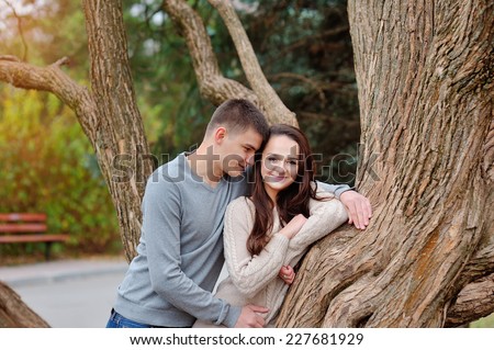 Young couple flirting in the green park. Girl holding phone going to call to boy.