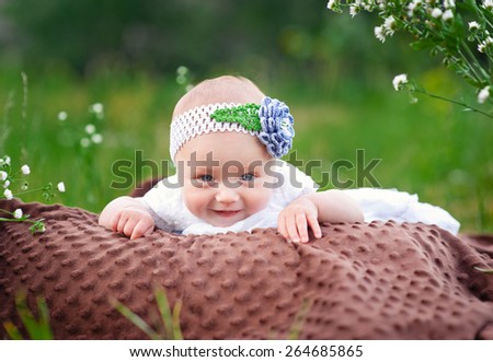Smiling little girl lying on a blanket in the park.