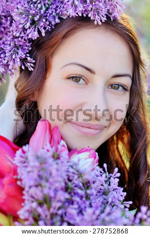 Beautiful girl with a bouquet of lilac in the hands walking in the spring park.