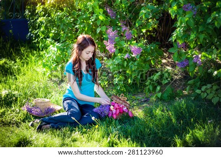 beautiful girl sitting on the grass with a bouquet of lilac in the spring park