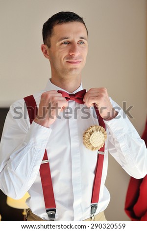 groom wears a red tie on a white shirt.