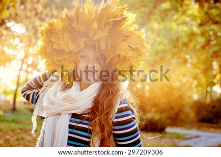 Young beautiful girl in autumn park with a wreath of yellow leaves on the head